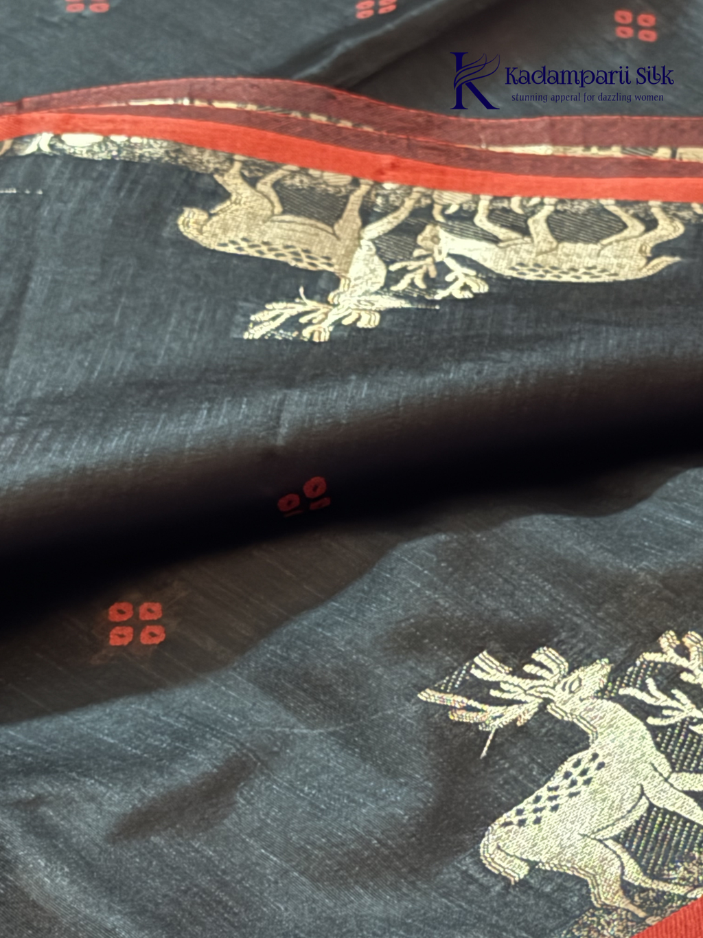 Black semi raw silk saree with red butta motifs, elegant zari woven border and pallu, soft lightweight texture, tassel detailing, and traditional ethnic styling by Kadamparii Silk.