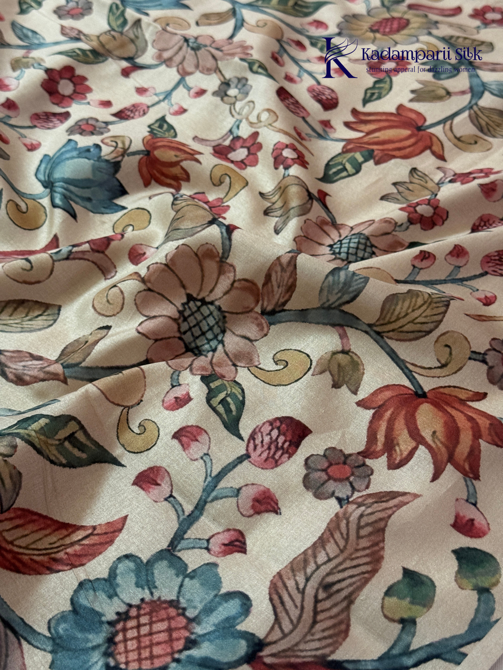 Beige silk cotton saree with colorful Kalamkari-inspired appliqué floral work, elegant woven golden border, handcrafted artistic detailing, soft texture, tassel finish, and graceful traditional drape by Kadamparii Silk.