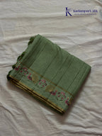 Sage green Tussar silk saree with embroidered peacock and floral border, subtle zari detailing, textured lightweight fabric, tassel finish, and elegant traditional styling by Kadamparii Silk.