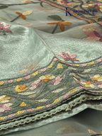 Pastel blue organza saree with multicolor floral embroidery, delicate vine patterns, embroidered border detailing, lightweight sheer fabric, and elegant festive styling by Kadamparii Silk.