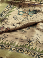 Soft Tussar saree with traditional pencil art print featuring mythological village scene motifs, subtle olive green zari border, artistic hand-drawn style detailing, and elegant lightweight drape by Kadamparii Silk.