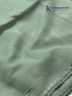 Sage green super net saree with elegant wave-pattern fancy embroidery, subtle shimmer detailing, delicate lace border, lightweight sheer texture, and graceful contemporary drape by Kadamparii Silk.