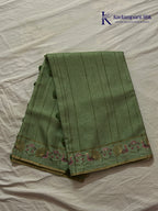 Sage green Tussar silk saree with embroidered peacock and floral border, subtle zari detailing, textured lightweight fabric, tassel finish, and elegant traditional styling by Kadamparii Silk.