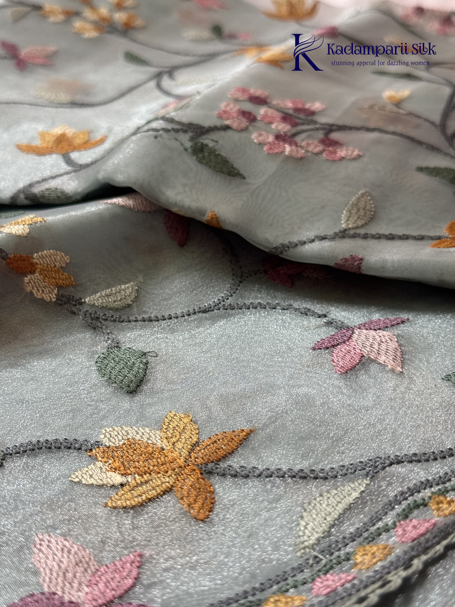 Pastel blue organza saree with multicolor floral embroidery, delicate vine patterns, embroidered border detailing, lightweight sheer fabric, and elegant festive styling by Kadamparii Silk.