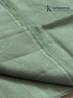 Sage green super net saree with elegant wave-pattern fancy embroidery, subtle shimmer detailing, delicate lace border, lightweight sheer texture, and graceful contemporary drape by Kadamparii Silk.