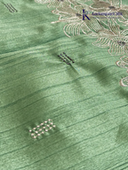 Emerald green semi raw silk saree with intricate floral embroidery, delicate embellishment detailing, rich textured finish, elegant tassels, and graceful festive drape by Kadamparii Silk.