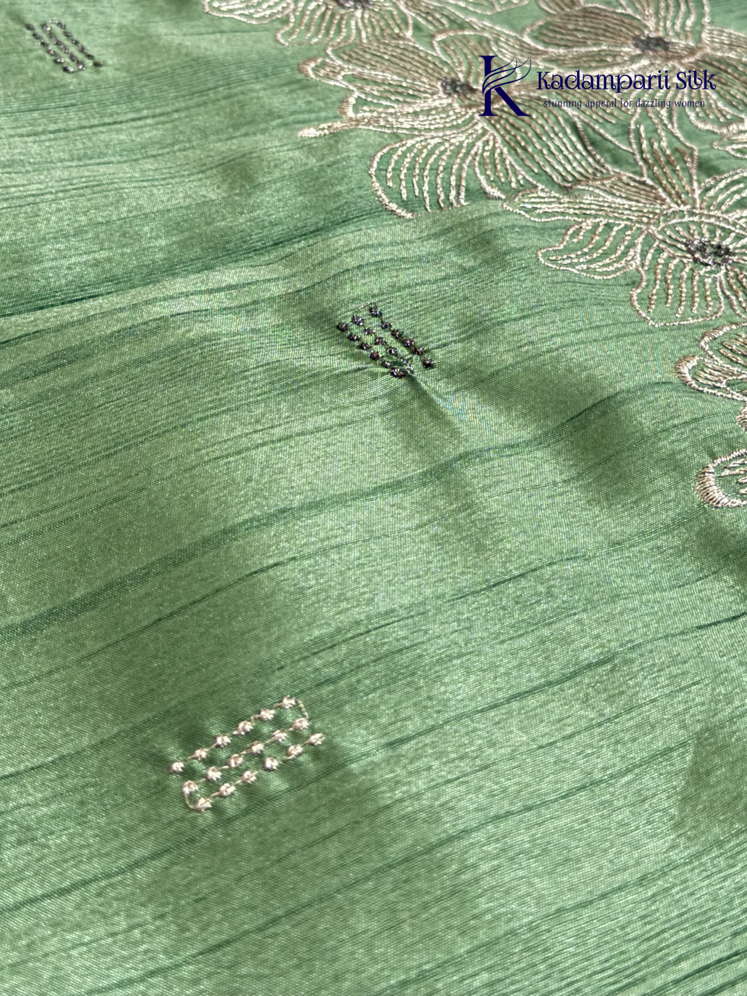 Emerald green semi raw silk saree with intricate floral embroidery, delicate embellishment detailing, rich textured finish, elegant tassels, and graceful festive drape by Kadamparii Silk.