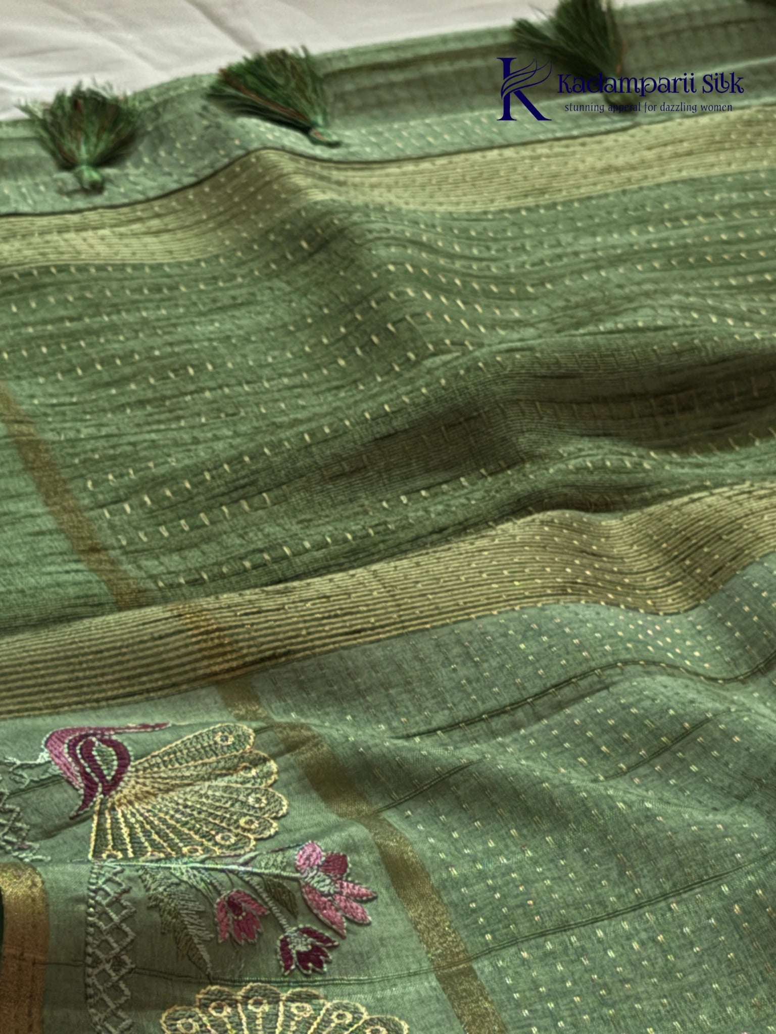 Sage green Tussar silk saree with embroidered peacock and floral border, subtle zari detailing, textured lightweight fabric, tassel finish, and elegant traditional styling by Kadamparii Silk.