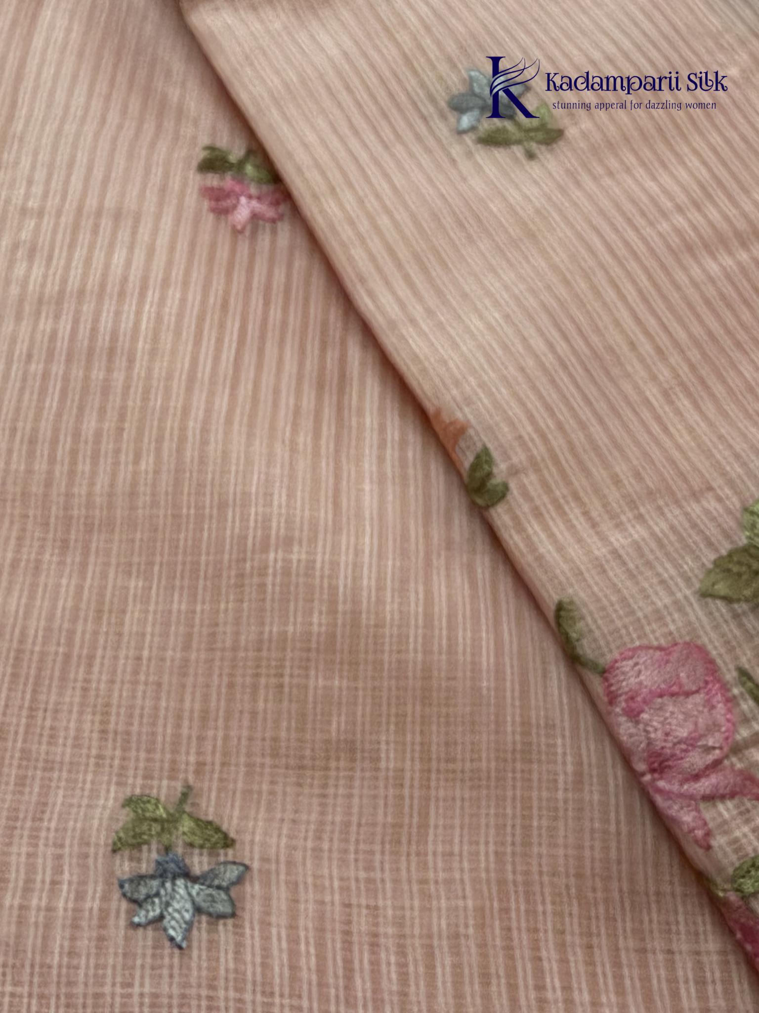 Blush pink super net saree with delicate multicolor floral embroidery, soft textured weave, lightweight sheer fabric, elegant feminine detailing, and graceful modern drape by Kadamparii Silk.