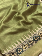 Soft Tussar saree with traditional pencil art print featuring mythological village scene motifs, subtle olive green zari border, artistic hand-drawn style detailing, and elegant lightweight drape by Kadamparii Silk.