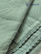 Sage green super net saree with elegant wave-pattern fancy embroidery, subtle shimmer detailing, delicate lace border, lightweight sheer texture, and graceful contemporary drape by Kadamparii Silk.