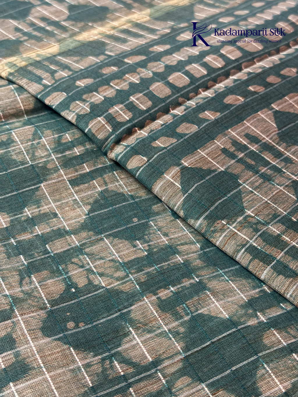 Kadamparii Silk teal semi tussar batik printed saree with abstract geometric patterns, subtle golden woven accents, soft textured fabric, tassel detailing, and elegant traditional design.