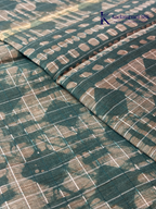 Kadamparii Silk teal semi tussar batik printed saree with abstract geometric patterns, subtle golden woven accents, soft textured fabric, tassel detailing, and elegant traditional design.