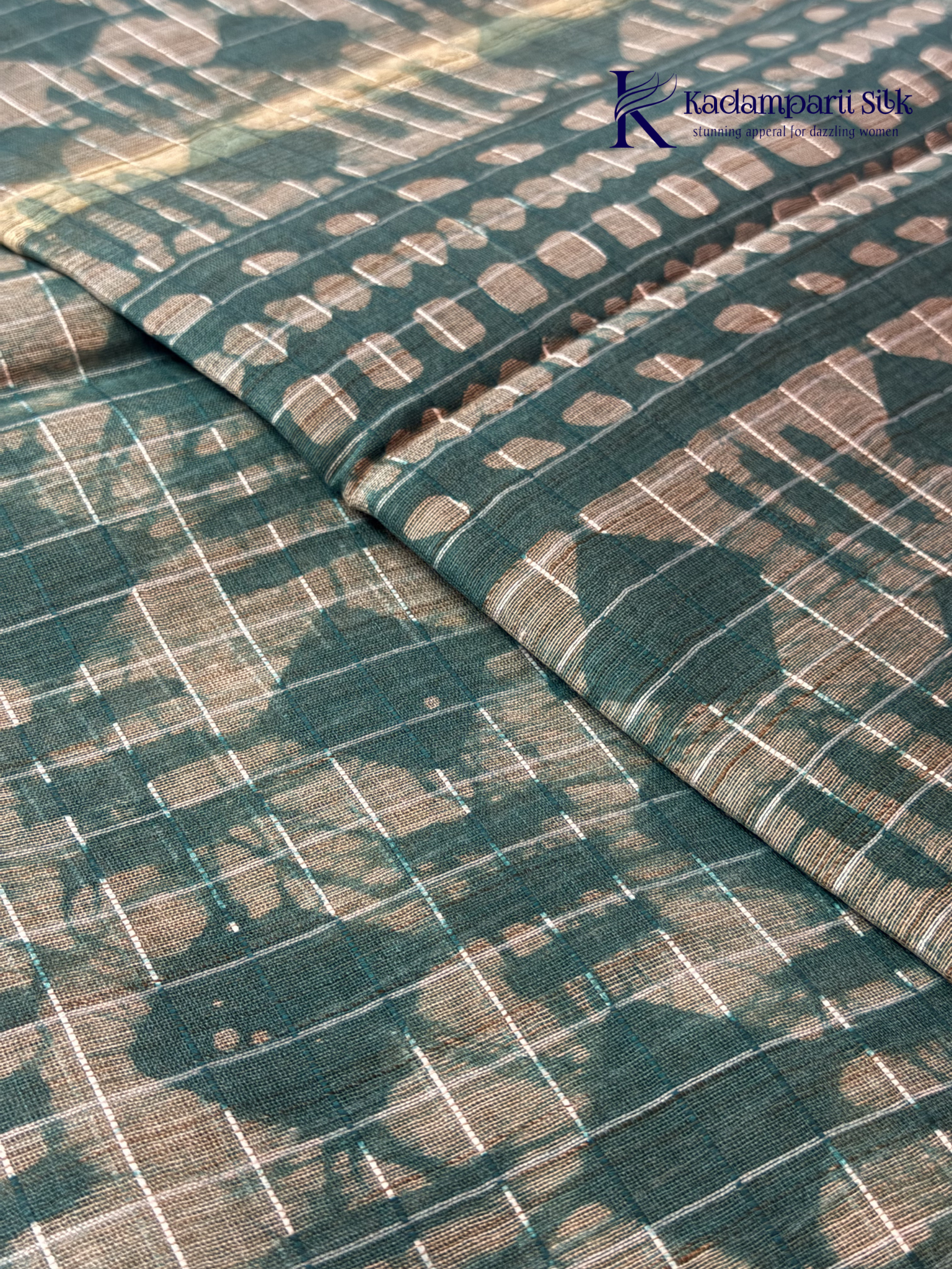 Kadamparii Silk teal semi tussar batik printed saree with abstract geometric patterns, subtle golden woven accents, soft textured fabric, tassel detailing, and elegant traditional design.