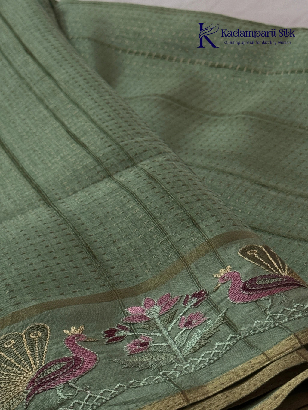 Sage green Tussar silk saree with embroidered peacock and floral border, subtle zari detailing, textured lightweight fabric, tassel finish, and elegant traditional styling by Kadamparii Silk.