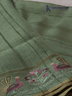 Sage green Tussar silk saree with embroidered peacock and floral border, subtle zari detailing, textured lightweight fabric, tassel finish, and elegant traditional styling by Kadamparii Silk.