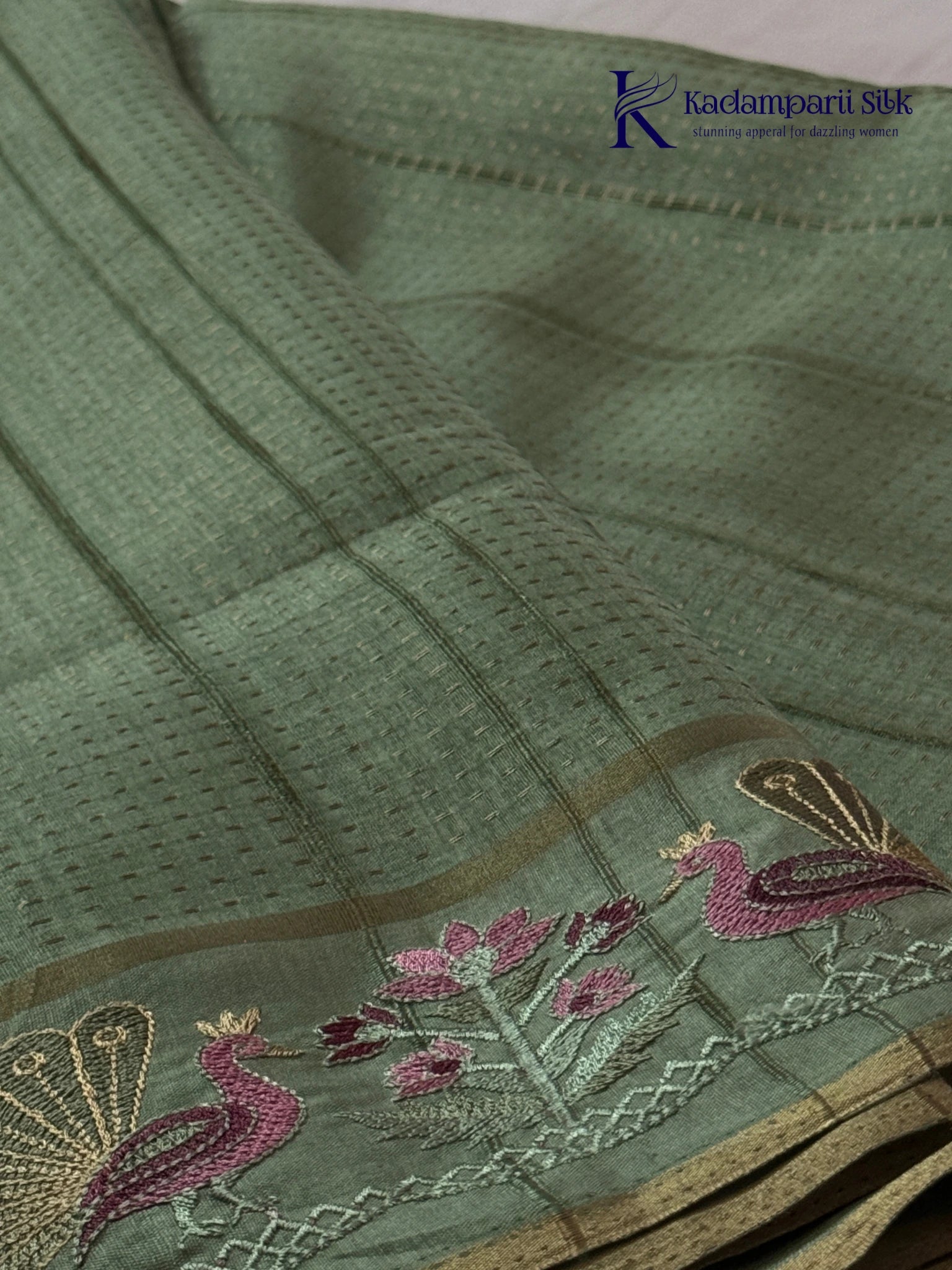 Sage green Tussar silk saree with embroidered peacock and floral border, subtle zari detailing, textured lightweight fabric, tassel finish, and elegant traditional styling by Kadamparii Silk.