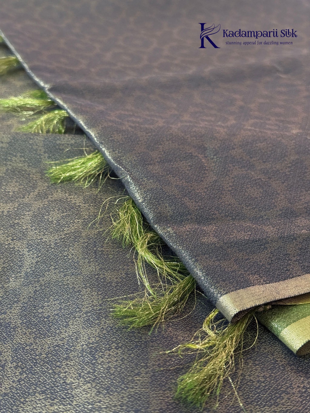 Charcoal grey semi Tussar jacquard saree with intricate woven self-patterns, subtle silver zari border, soft textured finish, elegant tassels, and lightweight graceful drape by Kadamparii Silk.