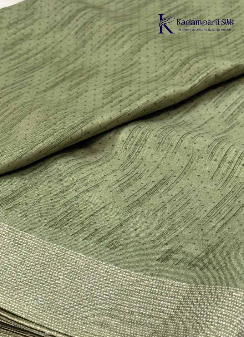 Kadamparii Silk olive green soft tussar silk saree with textured woven body and silver zari border, displayed on a white background.