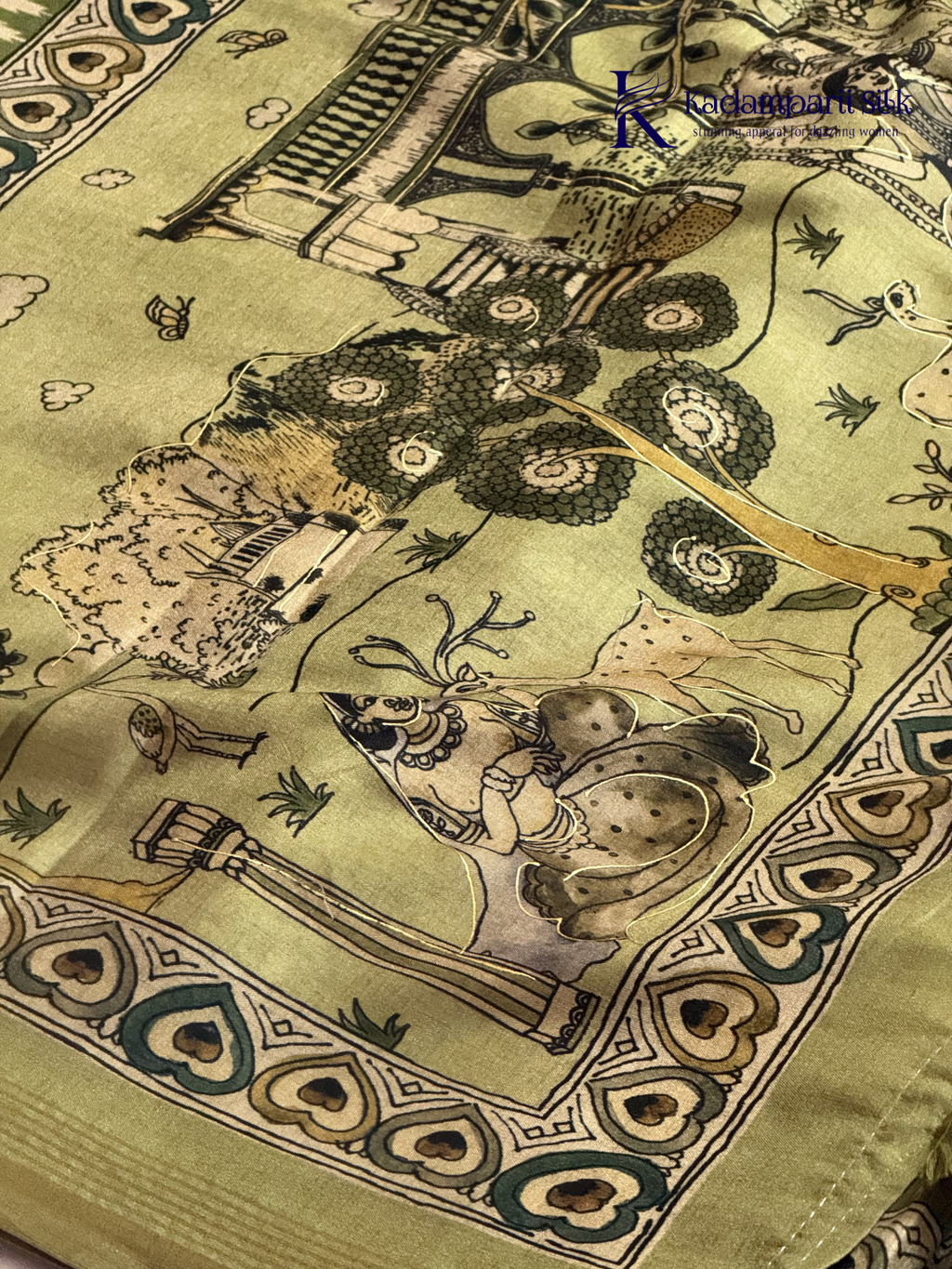 Soft Tussar saree with traditional pencil art print featuring mythological village scene motifs, subtle olive green zari border, artistic hand-drawn style detailing, and elegant lightweight drape by Kadamparii Silk.