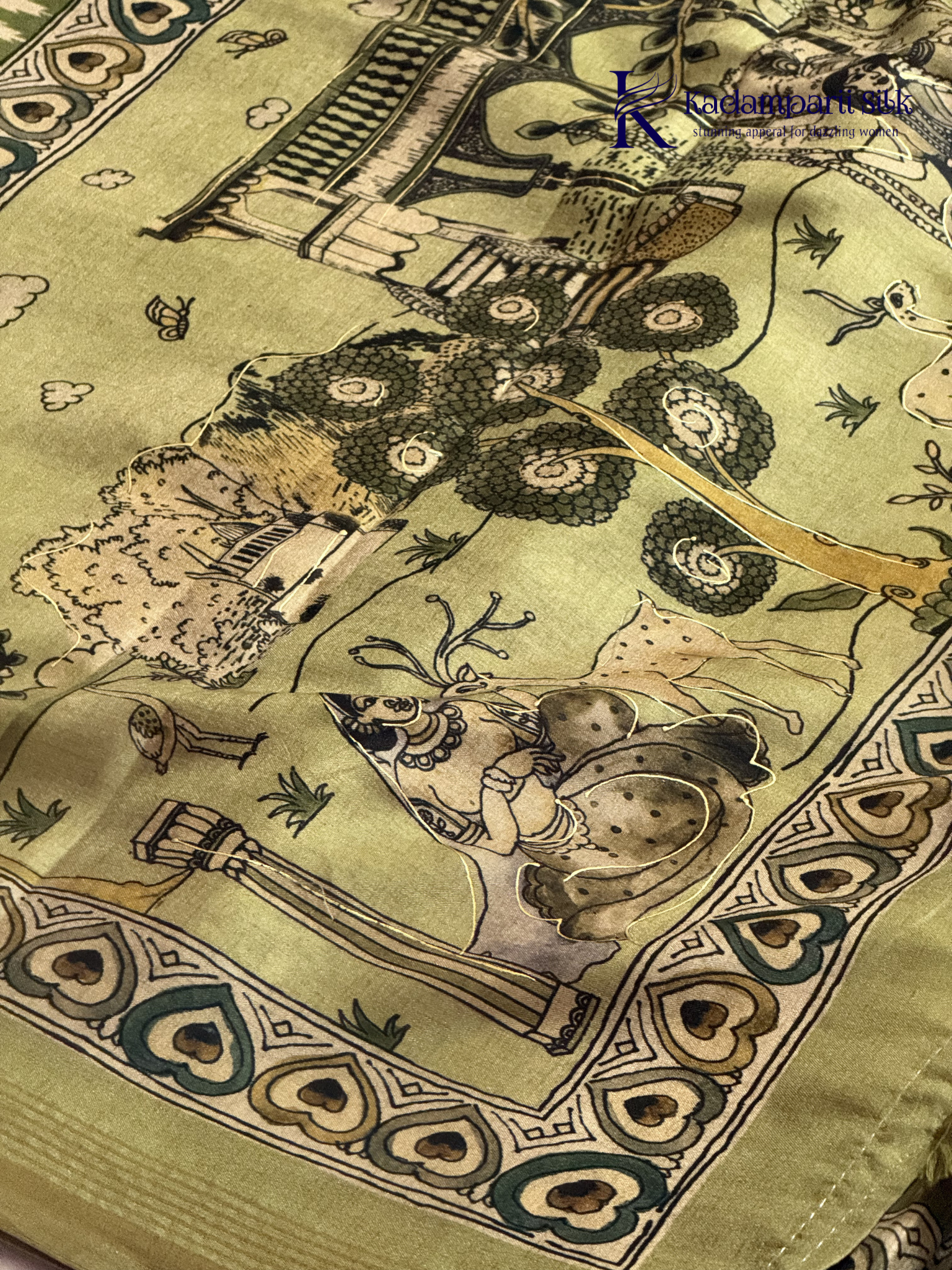Soft Tussar saree with traditional pencil art print featuring mythological village scene motifs, subtle olive green zari border, artistic hand-drawn style detailing, and elegant lightweight drape by Kadamparii Silk.