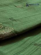 Emerald green semi raw silk saree with intricate floral embroidery, delicate embellishment detailing, rich textured finish, elegant tassels, and graceful festive drape by Kadamparii Silk.