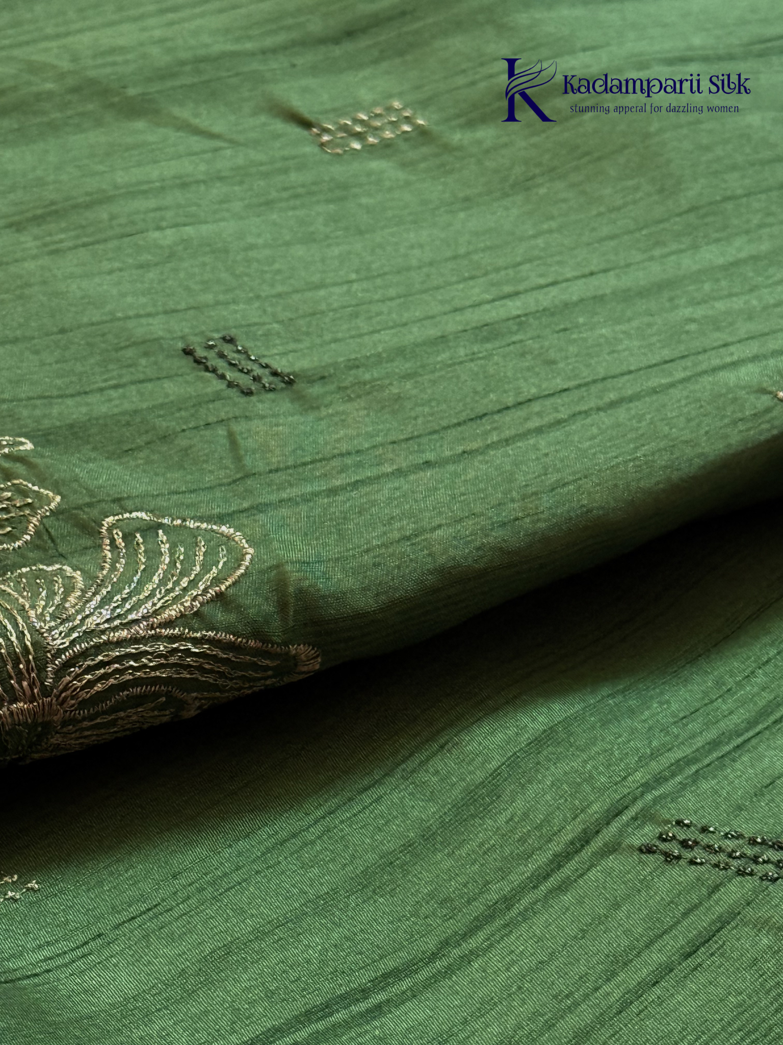 Emerald green semi raw silk saree with intricate floral embroidery, delicate embellishment detailing, rich textured finish, elegant tassels, and graceful festive drape by Kadamparii Silk.