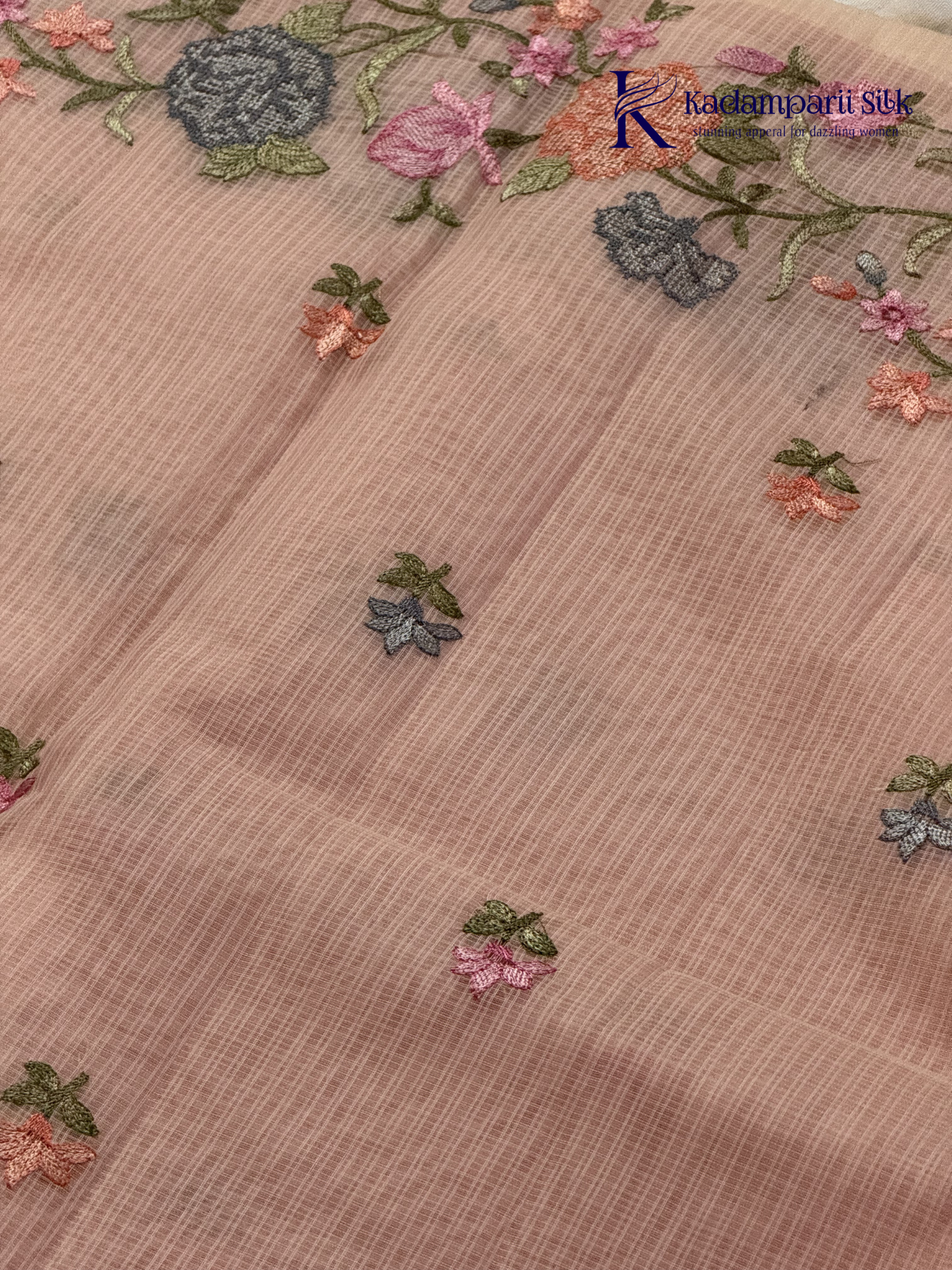 Blush pink super net saree with delicate multicolor floral embroidery, soft textured weave, lightweight sheer fabric, elegant feminine detailing, and graceful modern drape by Kadamparii Silk.