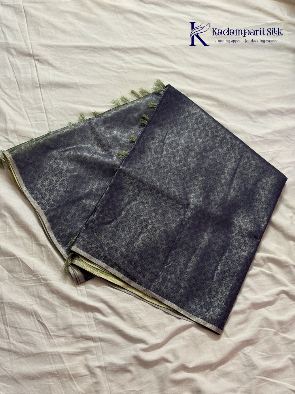 Charcoal grey semi Tussar jacquard saree with intricate woven self-patterns, subtle silver zari border, soft textured finish, elegant tassels, and lightweight graceful drape by Kadamparii Silk.
