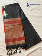 Black semi raw silk saree with red butta motifs, elegant zari woven border and pallu, soft lightweight texture, tassel detailing, and traditional ethnic styling by Kadamparii Silk.