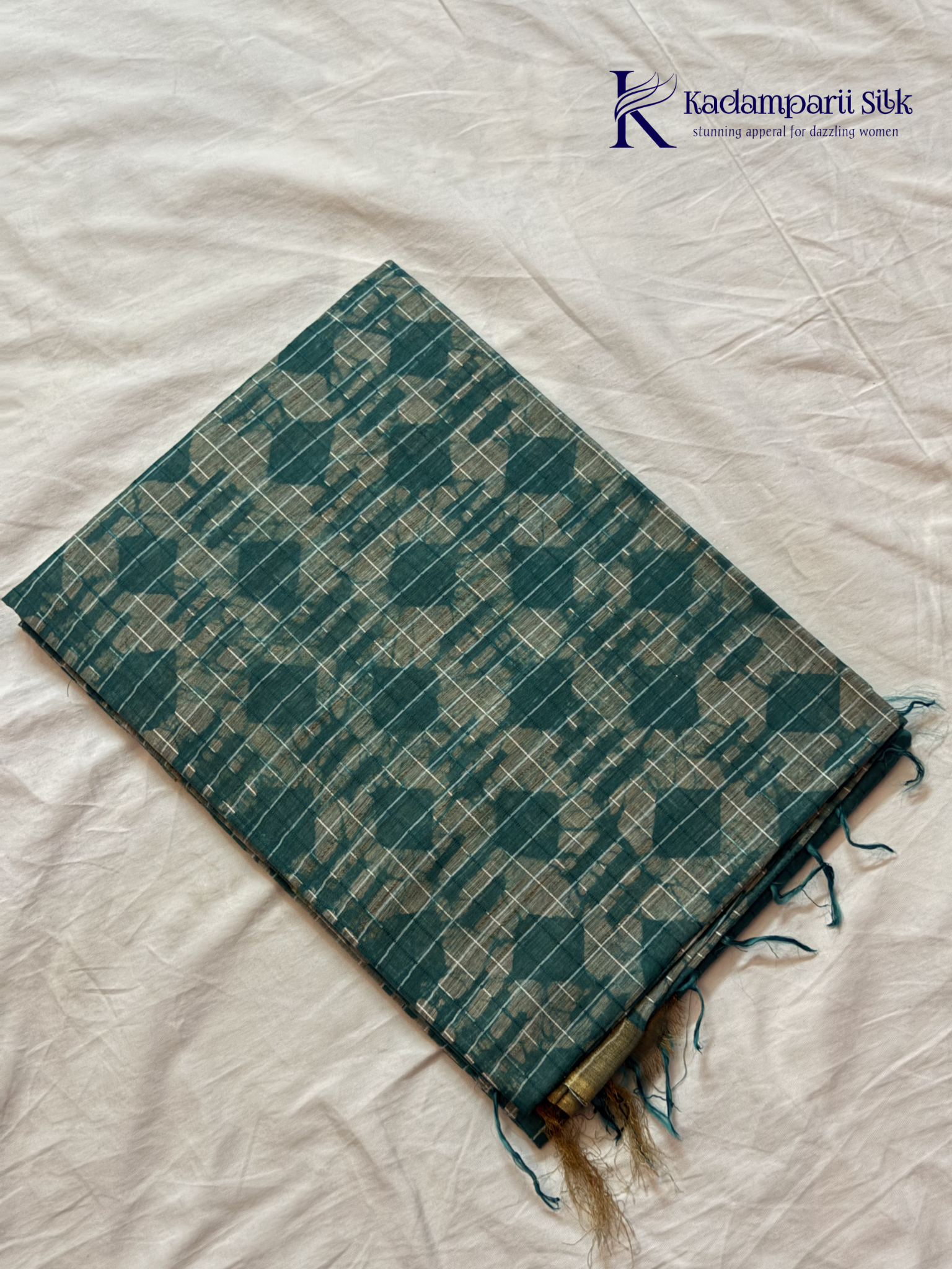 Kadamparii Silk teal semi tussar batik printed saree with abstract geometric patterns, subtle golden woven accents, soft textured fabric, tassel detailing, and elegant traditional design.