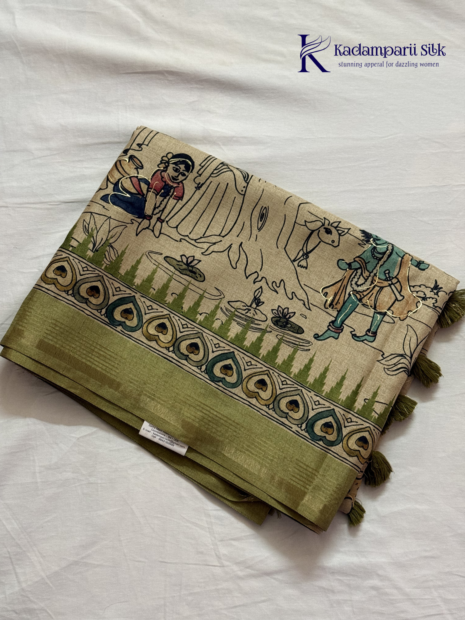 Soft Tussar saree with traditional pencil art print featuring mythological village scene motifs, subtle olive green zari border, artistic hand-drawn style detailing, and elegant lightweight drape by Kadamparii Silk.