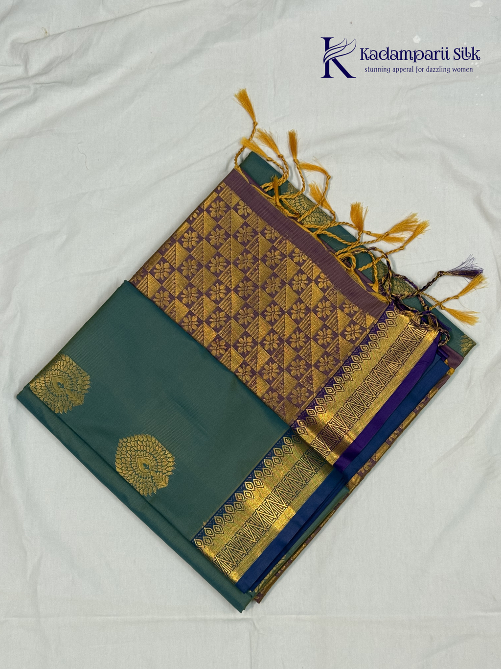 Kadamparii Silk teal blue semi soft silk saree with gold zari motifs, rich purple checkered zari pallu, ornate woven border, royal blue accents, and tassel detailing.