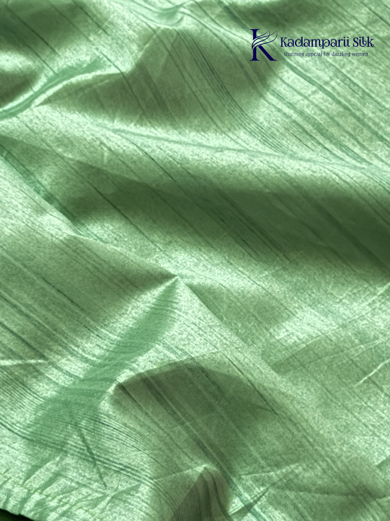 Emerald green semi raw silk saree with intricate floral embroidery, delicate embellishment detailing, rich textured finish, elegant tassels, and graceful festive drape by Kadamparii Silk.