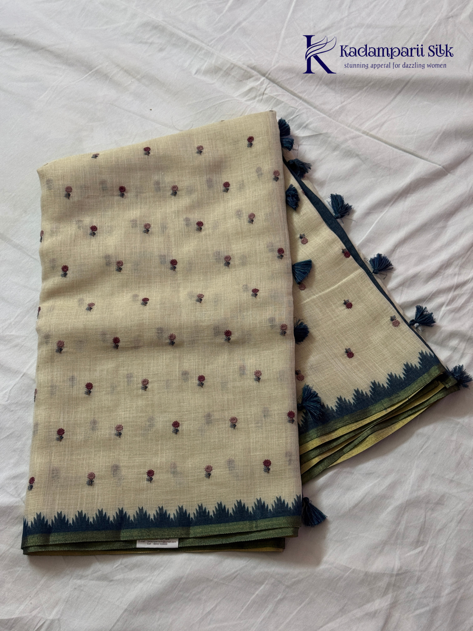 Ivory linen tissue saree with delicate handwork floral embroidery, elegant blue tissue pallu and border, soft lightweight texture, tassel detailing, and graceful ethnic styling by Kadamparii Silk.