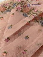 Blush pink super net saree with delicate multicolor floral embroidery, soft textured weave, lightweight sheer fabric, elegant feminine detailing, and graceful modern drape by Kadamparii Silk.