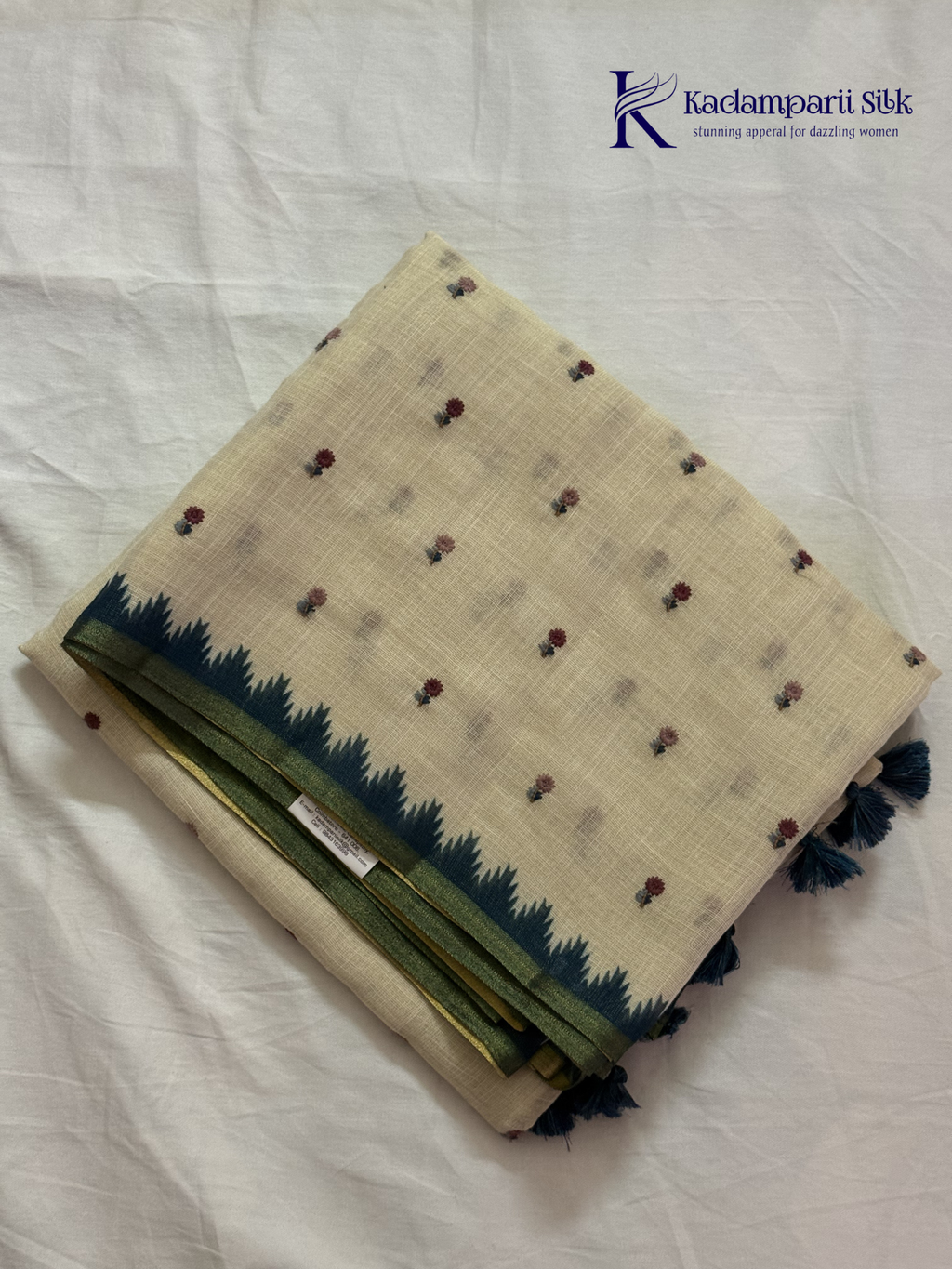 Ivory linen tissue saree with delicate handwork floral embroidery, elegant blue tissue pallu and border, soft lightweight texture, tassel detailing, and graceful ethnic styling by Kadamparii Silk.