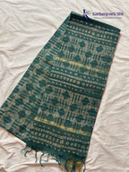 Kadamparii Silk teal semi tussar batik printed saree with abstract geometric patterns, subtle golden woven accents, soft textured fabric, tassel detailing, and elegant traditional design.
