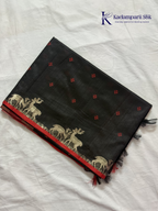 Black semi raw silk saree with red butta motifs, elegant zari woven border and pallu, soft lightweight texture, tassel detailing, and traditional ethnic styling by Kadamparii Silk.