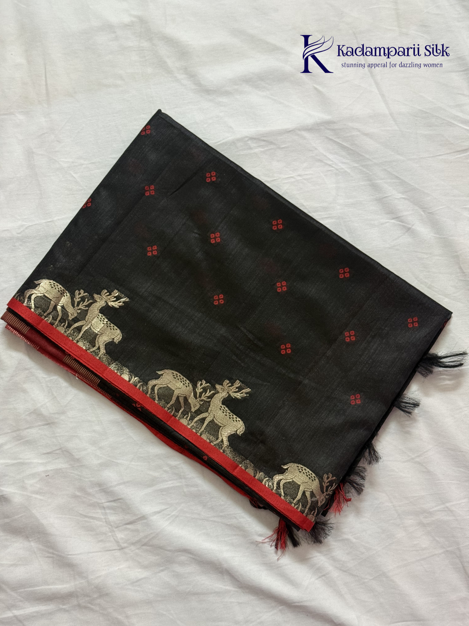 Black semi raw silk saree with red butta motifs, elegant zari woven border and pallu, soft lightweight texture, tassel detailing, and traditional ethnic styling by Kadamparii Silk.