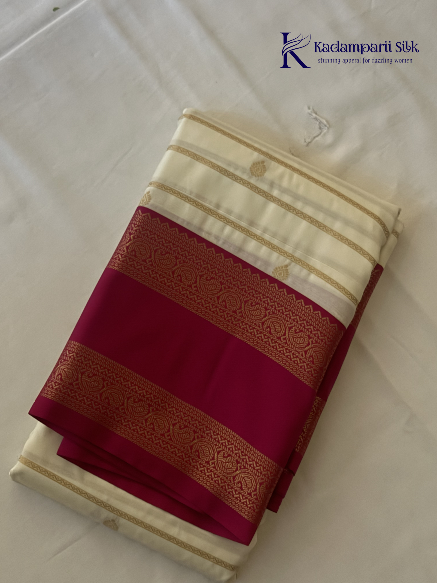 Off white art silk saree with rani pink zari border and traditional gold woven detailing displayed on white background Kadamparii Silk
