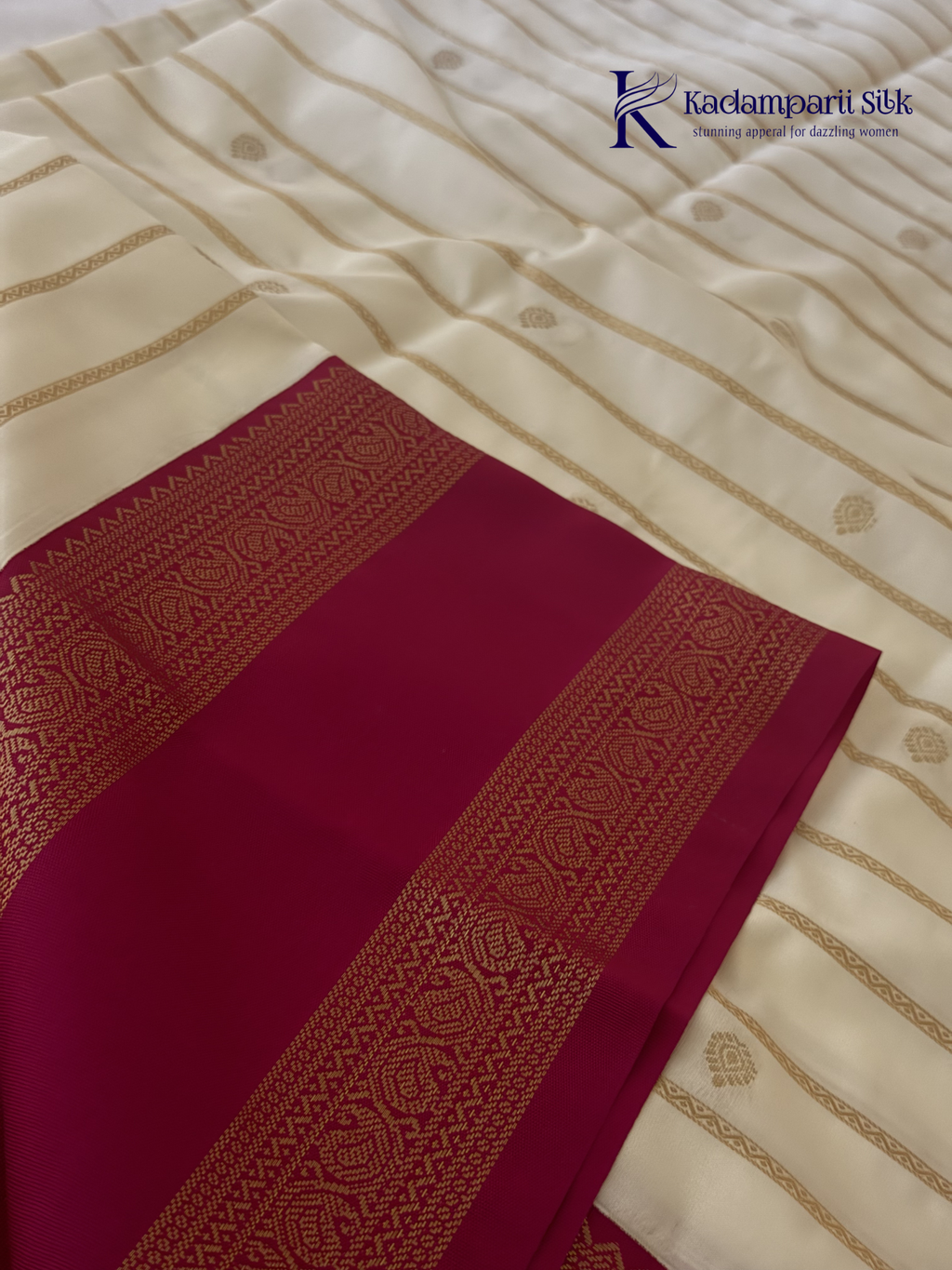 Off white art silk saree with rani pink zari border and traditional gold woven detailing displayed on white background