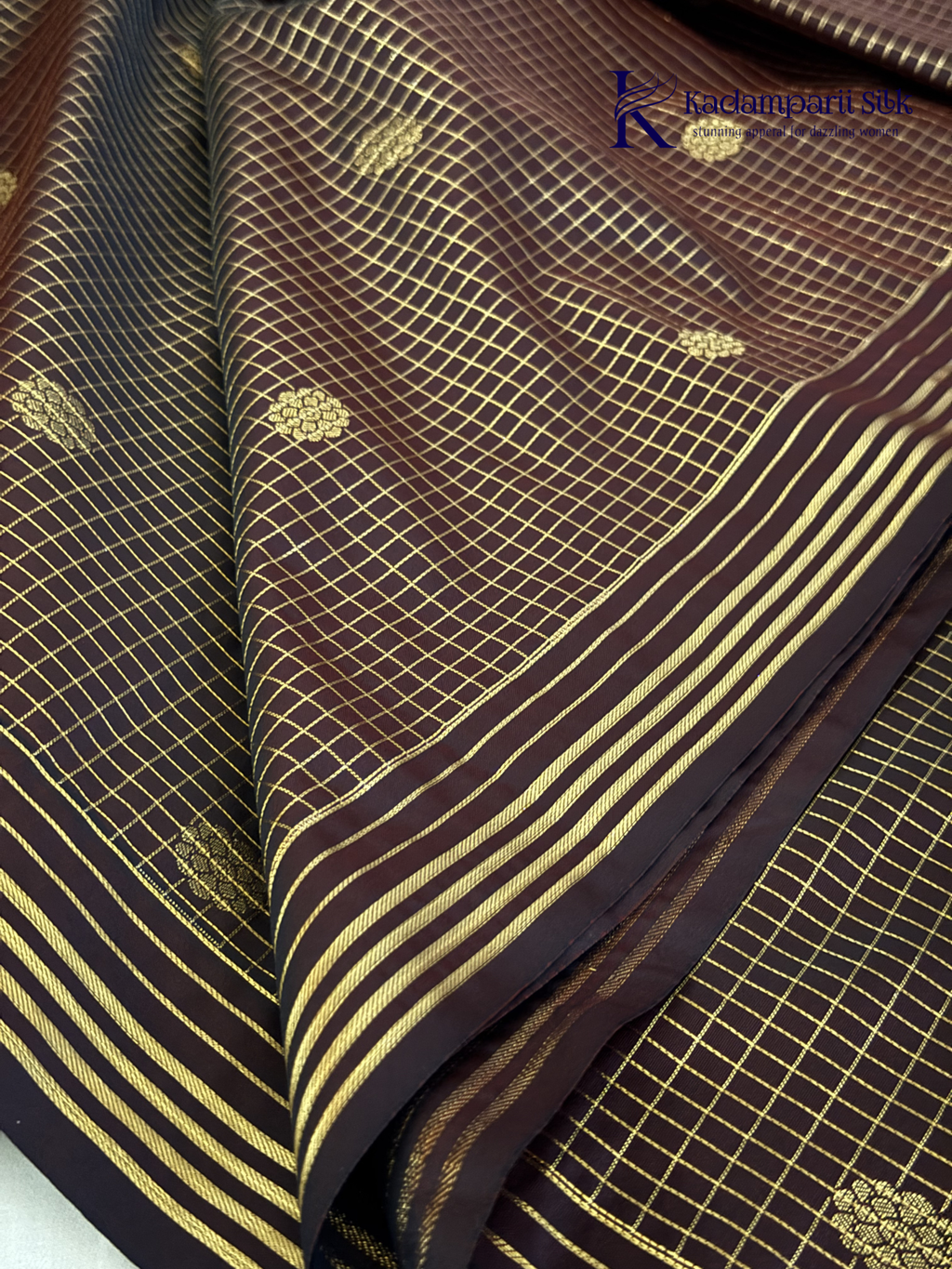 Kadamparii Silk dark chocolate semi soft silk saree with golden checked weaving, zari buttis, rich gold zari pallu, and tassel detailing.