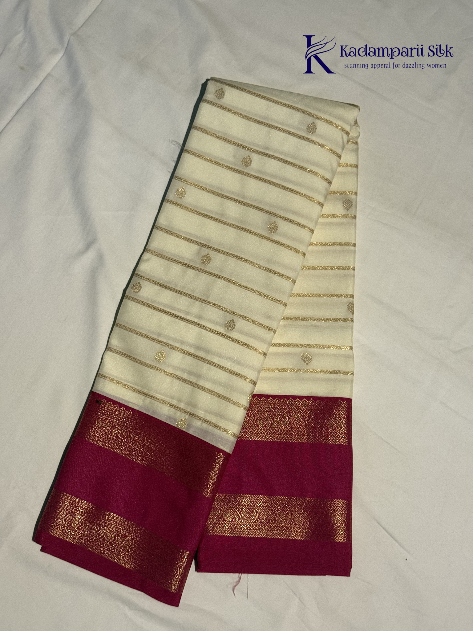 Off white art silk saree with rani pink zari border and traditional gold woven detailing displayed on white background