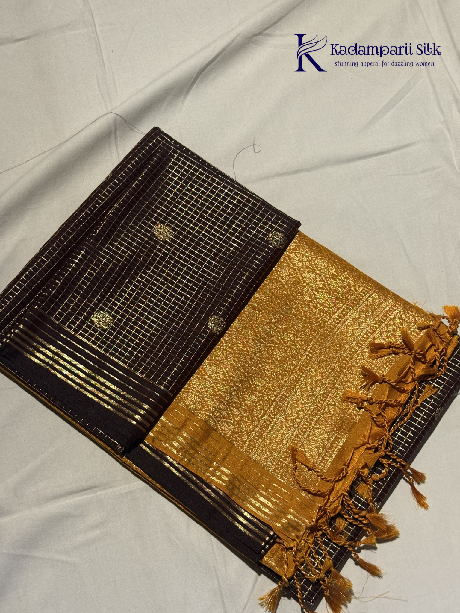 Kadamparii Silk dark chocolate semi soft silk saree with golden checked weaving, zari buttis, rich gold zari pallu, and tassel detailing.