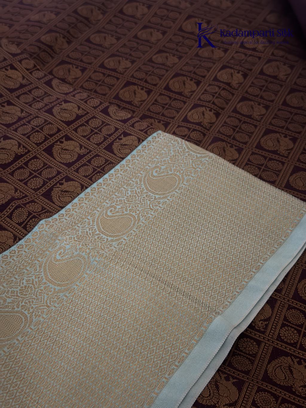 Chocolate brown art silk saree with ice blue zari woven border and traditional peacock motifs displayed on white background Kadamparii Silk