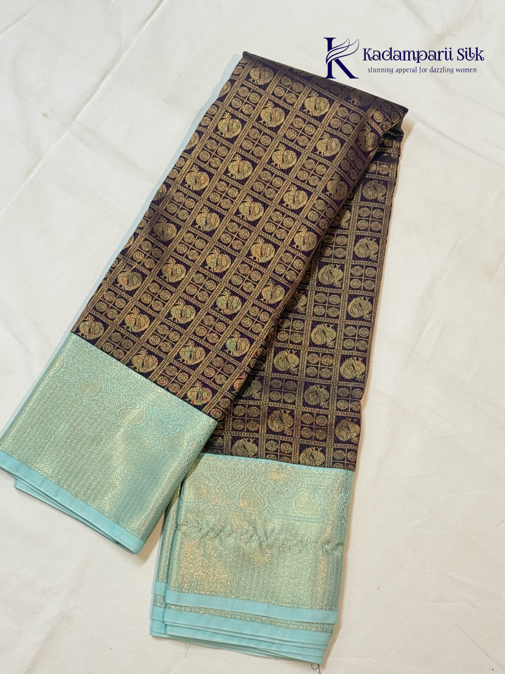 Chocolate brown art silk saree with ice blue zari woven border and traditional peacock motifs displayed on white background Kadamparii Silk