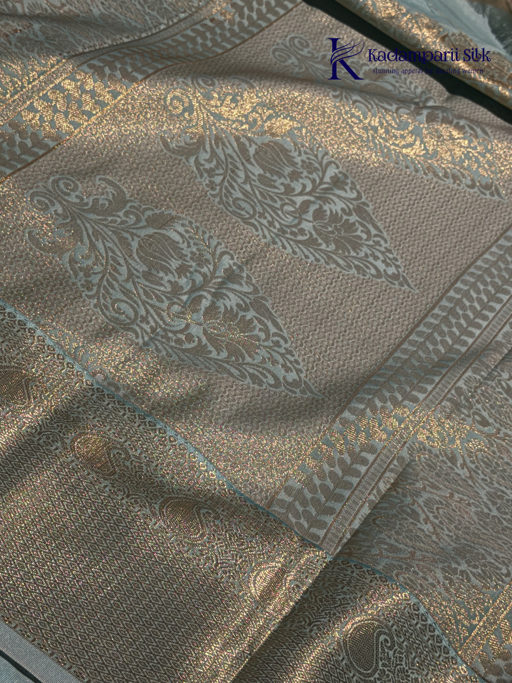 Chocolate brown art silk saree with ice blue zari woven border and traditional peacock motifs displayed on white background Kadamparii Silk