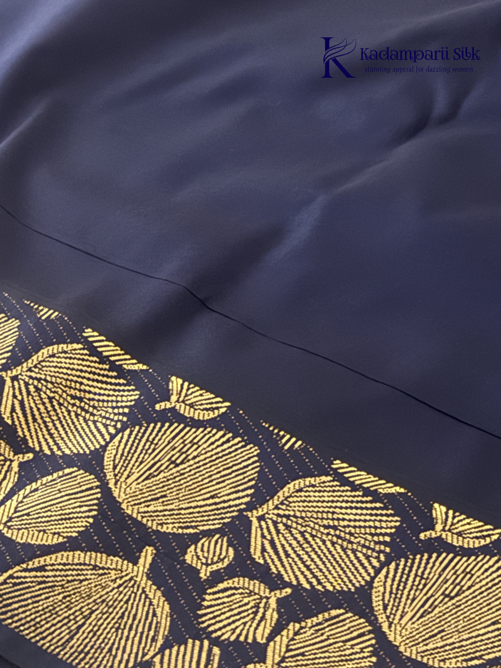 Mustard yellow art silk saree with navy blue floral zari border and textured weave displayed on white background Kadamparii SIlk