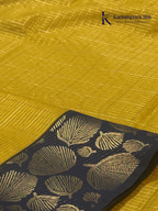 Mustard yellow art silk saree with navy blue floral zari border and textured weave displayed on white background Kadamparii SIlk